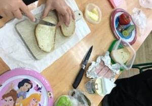 na stoliku widzimy różne produkty do przygotowania kanapek - pieczywo, warzywa, masło